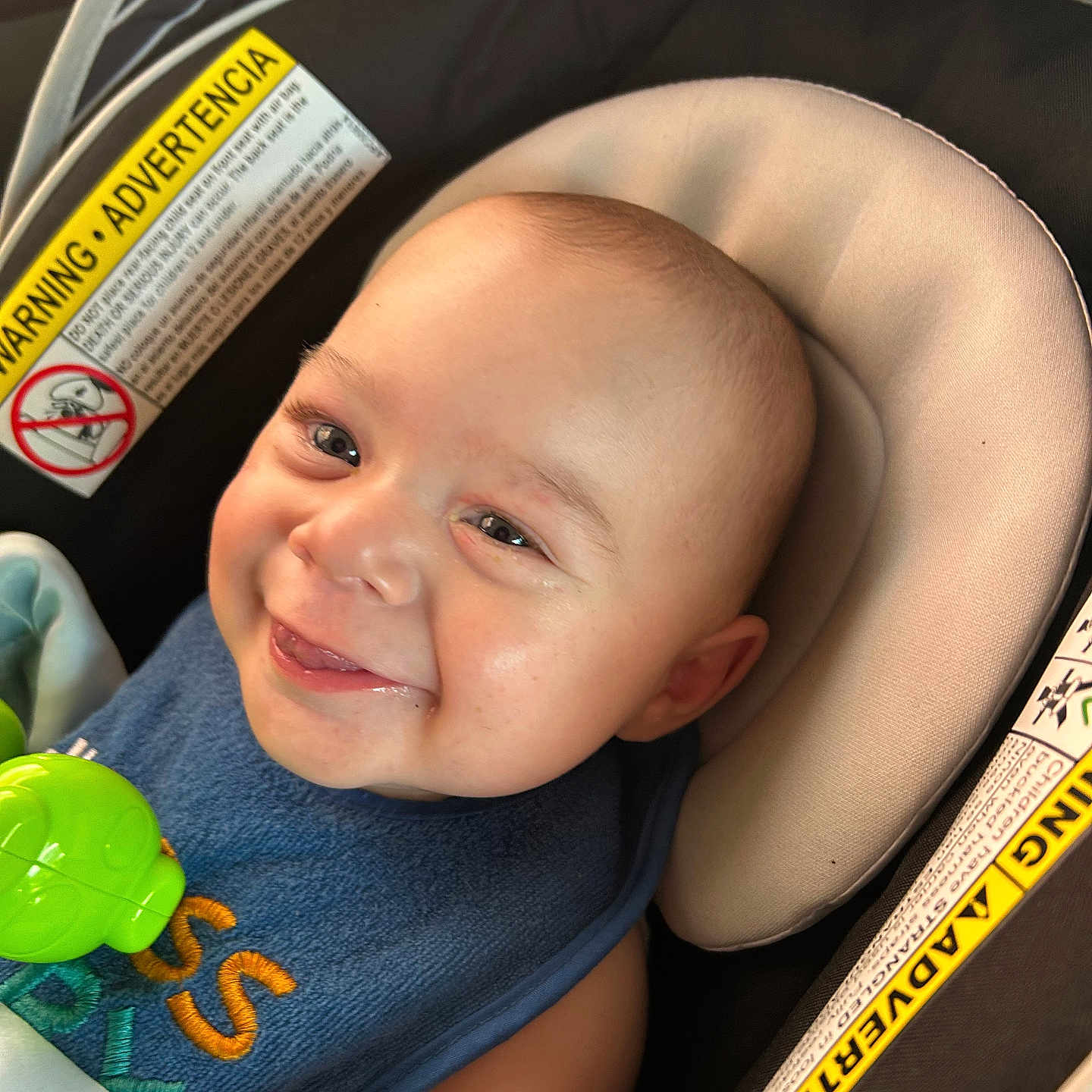 Nio joined the competition — help win amazing prizes! baby, blue_bib, car_seat, child, close_up, comfort, expression, face, green_toy, happy, head, indoor, infant, padded_seat, person, seat_belt, skin, smiling, toy, warning_label