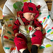 Nio is registered to the contest to win money with this photo: baby, baby_seat, black_socks, carpet, child, comfort, cute, face, furniture, hand, headwear, indoors, infant, patterned_fabric, peaceful, plush, red_clothing, rest, sleeping, toddler