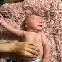 Nio is registered to the contest to win money with this photo: baby, infant, diaper, hand, blanket, pink, fluffy, skin, lying_down, adult_hand, tummy, cute, child, newborn, soft_texture, relaxed, indoor, human, person, comfort