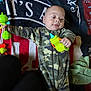 Nio joined the competition — help win amazing prizes! baby, child, infant, camouflage, pajamas, toy, green_toy, blanket, lying_down, curious, hands, face, expression, indoor, soft_texture, colorful, playful, cute, person, young_child
