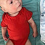 arms, baby, bed, black_socks, blanket, child, comfort, curious_expression, cute, head, indoors, infant, legs, lying_down, onesie, person, portrait, red_clothing, skin, soft_texture