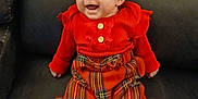 Brooke is registered to the contest to win money with this photo: baby, child, smile, red_clothing, plaid, headband, sitting, couch, happy, infant, portrait, indoors, cute, person, fashion, warm_clothing, young_child, accessory, feet, buttoned_shirt