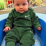 Brooke joined the competition — help win amazing prizes! baby, child, green_clothing, nike_logo, blue_chair, indoor, play_area, baby_gate, toy, carpet, curious, seated, infant, face, expression, sock, playroom, person, portrait, casual