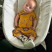Caleb joined the competition — help win amazing prizes! baby, infant, baby_nest, yellow_outfit, lion_print, sneakers, white_texture, baby_bedding, cute, portrait, child, footwear, candid, indoor, soft_light, small_child, comfortable, relaxed, curious, person