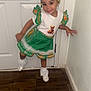 child, girl, smile, dress, green, white, hair_accessories, shoes, socks, door, wall, floor, indoor, pose, happy, cute, fashion, playful, young_child, portrait