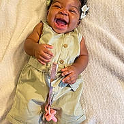 Klani Byrd is registered to the contest to win money with this photo: baby, child, smiling, happy, pacifier, romper, clothing, hair_bows, blanket, infant, cute, joyful, lying_down, skin, hand, feet, toddler, indoors, playful, expression