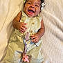 baby, child, smiling, happy, pacifier, romper, clothing, hair_bows, blanket, infant, cute, joyful, lying_down, skin, hand, feet, toddler, indoors, playful, expression