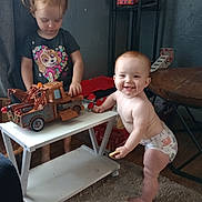 Heaven is registered to the contest to win money with this photo: toddler, baby, child, toy, truck, table, diaper, smile, playing, indoor, carpet, furniture, person, cute, expression, hair, shelf, cookie, clothing, room