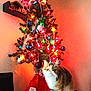 cat, christmas_tree, ornaments, colorful_lights, holiday, festive, indoor, decorations, tree_skirt, santa_claus, red, green, white, feline, curious, pet, domestic_animal, celebration, home, seasonal