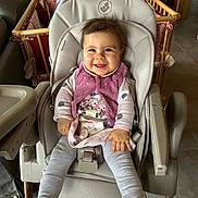 Pauline participe au concours pour gagner de l'argent avec cette photo : baby, high_chair, smiling, indoor, child, pink_vest, polka_dot, animal_print, playpen, wooden_furniture, cozy, happy, toddler, seatbelt, floor_tile, long_sleeves, socks, hair, face, person