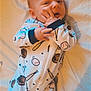 baby, infant, onesie, bed, baseball, glove, bat, sports_theme, child, sleepwear, cute, hand, face, portrait, lying_down, soft_light, indoors, playful, young_child, expression