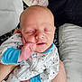 baby, infant, sleeping, hand, clothing, sleeper, blue_cuffs, face, closed_eyes, person, resting, comfort, cuddle, blanket, arm, bed, pillow, soft, peaceful, indoor