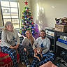 casual_clothing, christmas_tree, cozy, decorations, dog, family, festive, floor, holiday, indoor, pajamas, people, pets, plush_toy, room, seated, shadow, smiling, sunlight, window