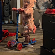 Suzie joined the competition — help win amazing prizes! toddler, child, scooter, indoor, onesie, pink_clothing, toy, floor, carpet, vacuum_cleaner, cabinet, door, plastic_bag, shadow, wood_floor, socks, furniture, play, cute, person