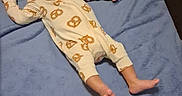Aurelio is registered to the contest to win money with this photo: baby, infant, blanket, onesie, pretzel_pattern, playpen, smiling, lying_down, indoors, soft_texture, child, cute, happy, person, foot, hand, head, face, sleepwear, cozy