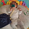baby, infant, pacifier, cushion, clothing, onesie, milestone, colorful, foam_letters, lying_down, cute, child, newborn, soft_fabric, portrait, one_month, baby_outfit, baby_boy, baby_girl, baby_sleeping