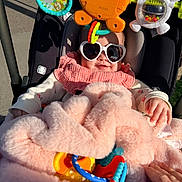 Mallory joined the competition — help win amazing prizes! accessory, baby, blanket, child, clothing, colorful, comfort, cute, face, hand, heart_shaped_glasses, infant, outdoor, person, pink, smiling, stroller, sunglasses, sunlight, toy