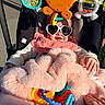 accessory, baby, blanket, child, clothing, colorful, comfort, cute, face, hand, heart_shaped_glasses, infant, outdoor, person, pink, smiling, stroller, sunglasses, sunlight, toy