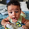 baby, infant, child, portrait, wide_eyed, surprised, smiling, curly_hair, brown_hair, face, eyes, hands, sleeveless, clothing, stuffed_toy, plush, blanket, bedroom, indoor, close_up