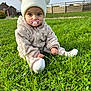 baby, child, grass, outdoor, pacifier, hat, pom_poms, beige_clothing, sitting, greenery, countryside, fence, house, cute, portrait, infant, winter_clothing, nature, young_child, daylight