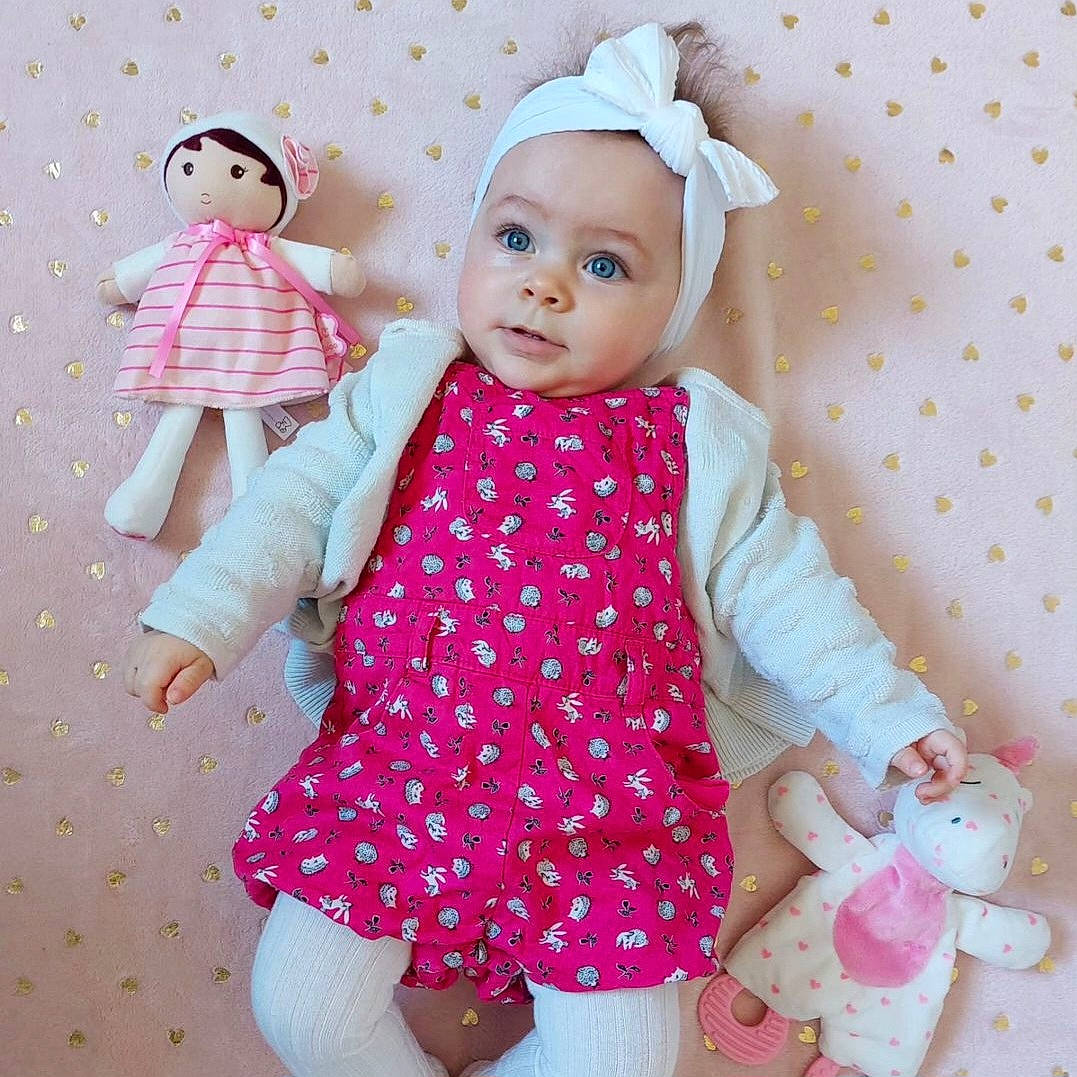 Léa a rejoint le concours — aidez-le/la à gagner de superbes lots ! baby_toddler_clothing, baby_toys, child, day_dress, doll, dress, dress_shirt, eyelash, headwear, linens, magenta, one_piece_garment, pattern, peach, person, pink, skin, sleeve, textile, toddler