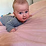 Mathias is registered to the contest to win money with this photo: baby, bed, blanket, child, cozy, cute, expression, eyes, face, furniture, gray_onesie, head_up, indoor, infant, lying_down, pink_bedspread, portrait, skin, smile, soft_lighting