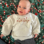 Ivy participe au concours pour gagner de l'argent avec cette photo : baby, infant, blanket, candy_cane_pattern, white_sweatshirt, text_on_clothing, hearts, gray_pants, lying_down, face, smiling, cute, cozy, festive, holidays, indoor, child, person, soft_texture, pacifier