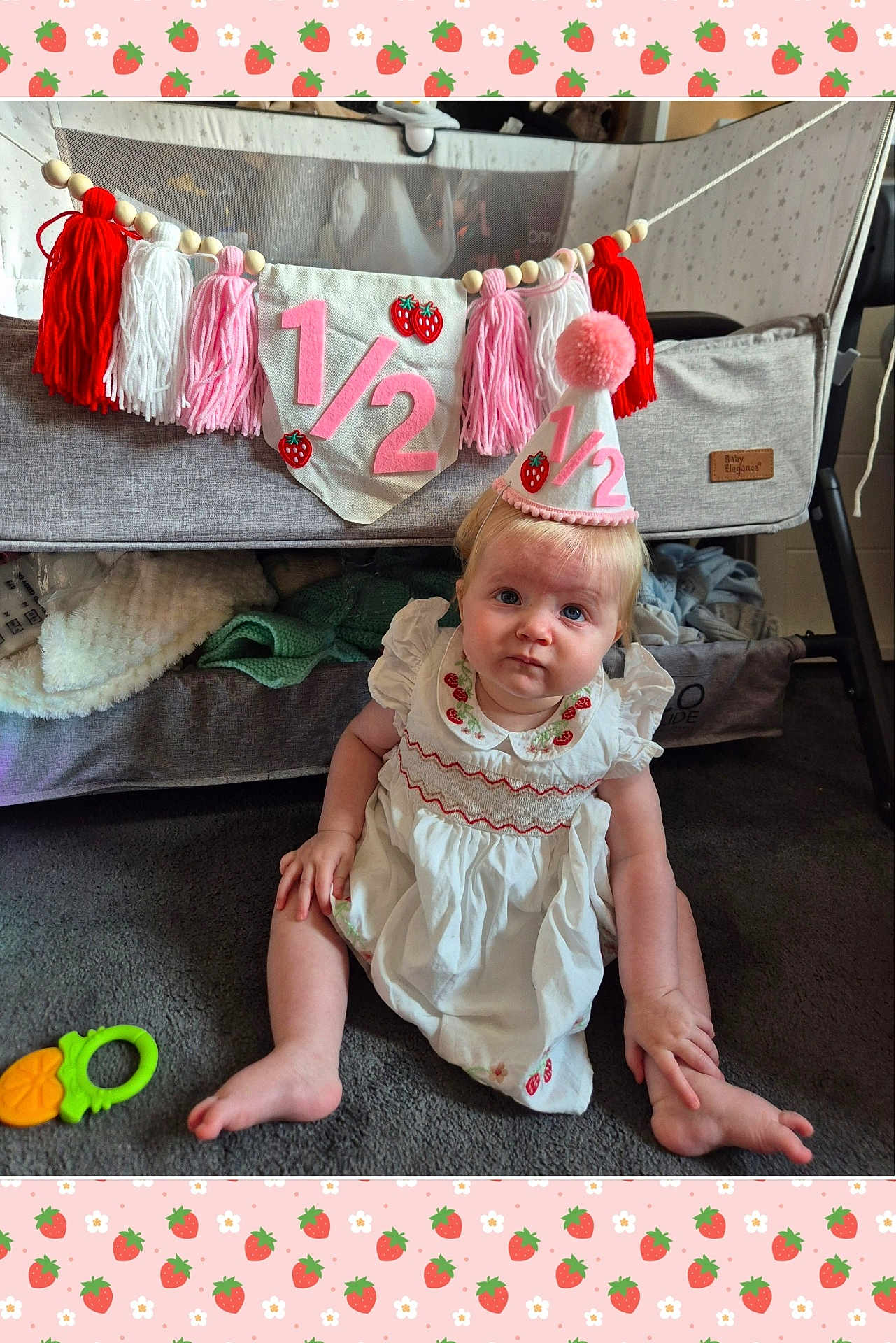 Romani joined the competition — help win amazing prizes! baby, child, party_hat, dress, carpet, crib, blanket, toy, tassel, banner, floor, indoor, decoration, cute, infant, sitting, curious, celebration, pink, white