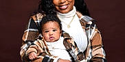 Mahdi joined the competition — help win amazing prizes! woman, baby, portrait, smile, plaid_jacket, matching_outfits, curly_hair, jewelry, necklace, casual_clothing, indoor, studio_lighting, person, holding, family, happy, cute, child, fashion, closeup