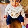 Ily a rejoint le concours — aidez-le/la à gagner de superbes lots ! baby, blue_pants, child, cozy, curious, cute, decor, floor, home, indoor, person, portrait, seated, smiling, socks, striped_socks, sweater, toddler, white, wooden_floor