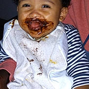 Noah -Lamine participe au concours pour gagner de l'argent avec cette photo : baby, bib, child, chocolate, closeup, cute, dark_background, face, food, hand, happy, holding, indoor, infant, mess, messy, person, portrait, smile, striped_clothing