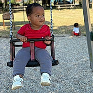 Noah -Lamine a rejoint le concours — aidez-le/la à gagner de superbes lots ! child, swing, playground, outdoor, park, trees, bench, grass, daylight, person, red_shirt, gray_pants, white_shoes, baby, play, fun, chain, seat, background, young