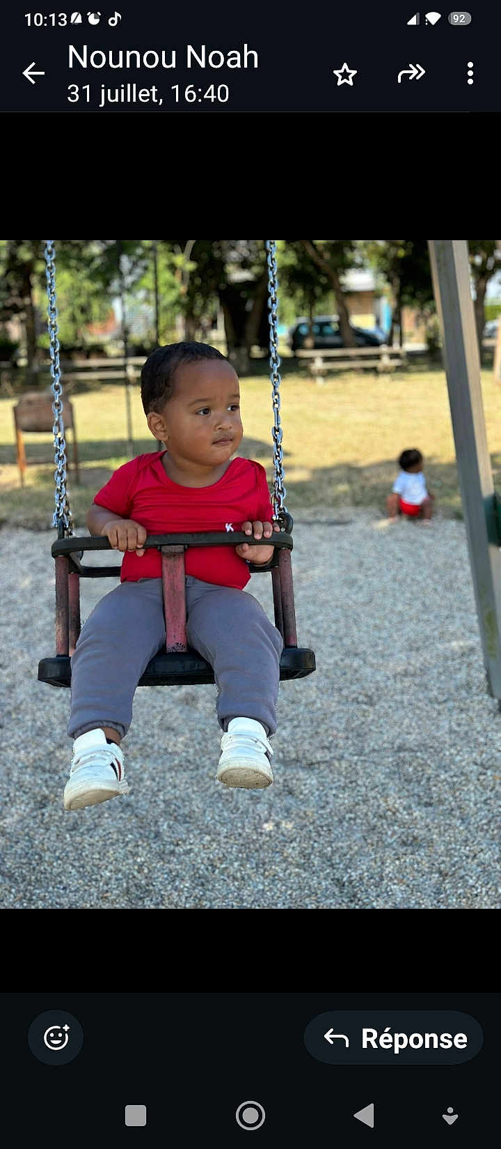 Noah -Lamine a rejoint le concours — aidez-le/la à gagner de superbes lots ! child, swing, playground, outdoor, park, trees, bench, grass, daylight, person, red_shirt, gray_pants, white_shoes, baby, play, fun, chain, seat, background, young