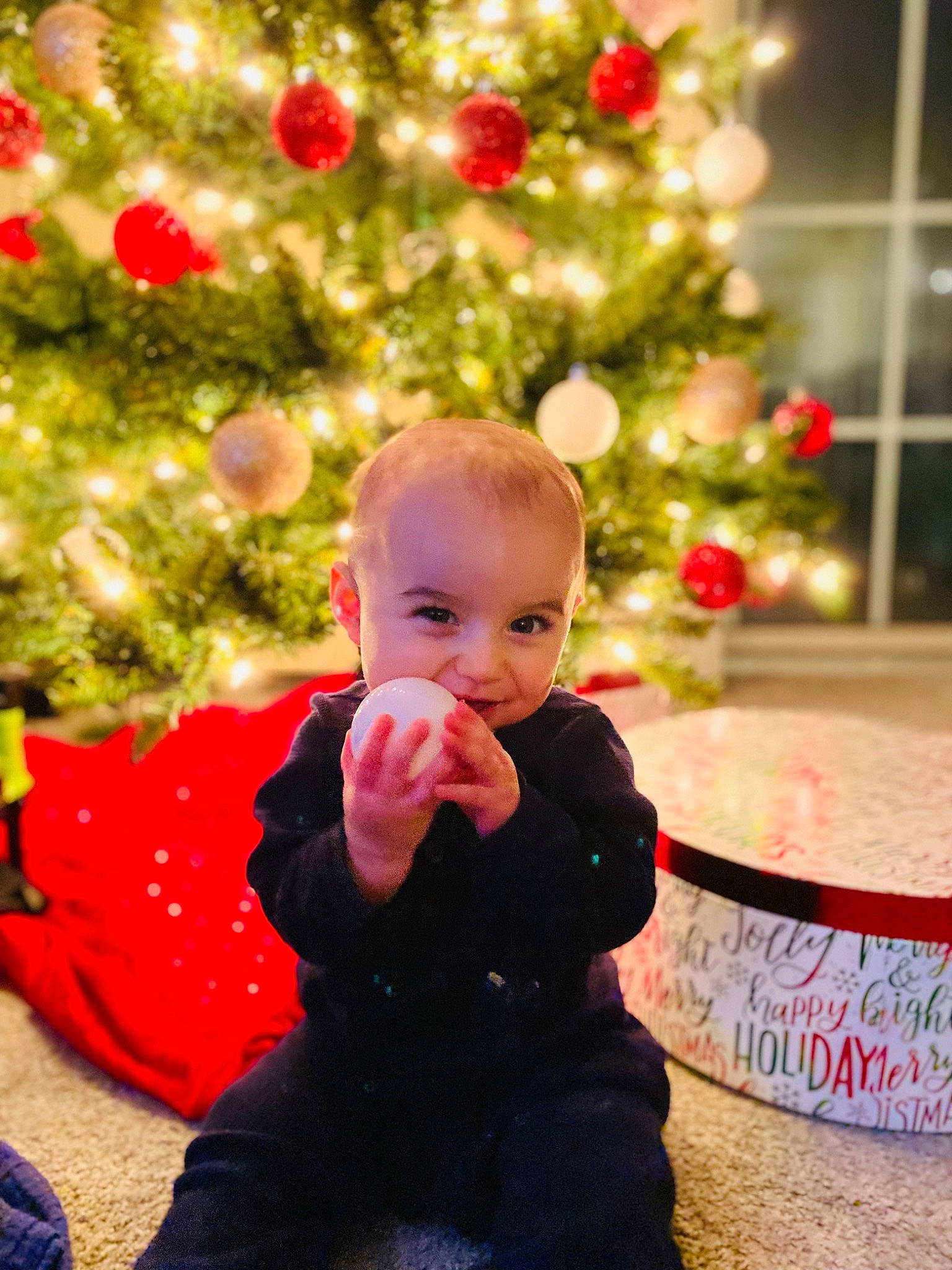 Kayden is registered to the contest to win money with this photo: baby, baby_toddler_clothing, child, christmas, christmas_decoration, christmas_eve, christmas_ornament, christmas_tree, conifer, event, fun, happy, holiday, holiday_ornament, ornament, person, plant, sitting, toddler, tree