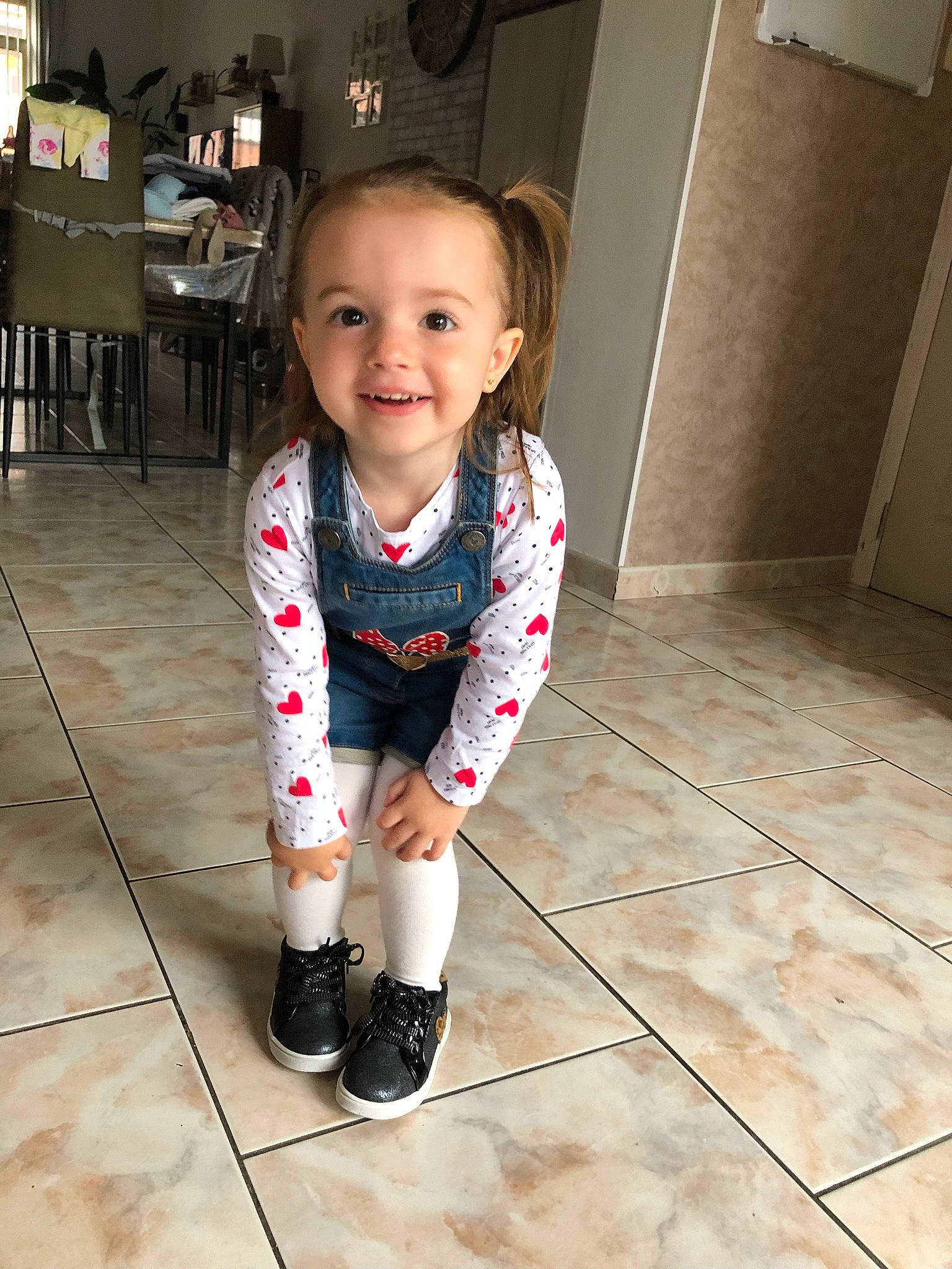Angelina participe au concours pour gagner de l'argent avec cette photo : baby, baby_toddler_clothing, child, eye, floor, flooring, fun, happy, hardwood, human_leg, joy, knee, laminate_flooring, pattern, person, sleeve, smile, standing, thigh, toddler