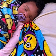 Niari joined the competition — help win amazing prizes! baby, sleeping, blanket, pacifier, emoji_pattern, colorful, infant, cozy, soft_lighting, closeup, face, curly_hair, pink_clothing, resting, peaceful, child, indoors, comfort, cute, young