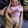baby, child, smiling, happy, face, clothing, onesie, teddy_bear_suit, bed, blanket, cozy, cute, infant, person, indoor, portrait, lying_down, hands, cheeks, expression