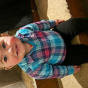 Lilia is registered to the contest to win money with this photo: candid, carpet, casual_clothing, child, colorful_clothing, cute, floor_tiles, hair_bow, happy, home, indoor, person, plaid_shirt, portrait, seated, smiling, sneakers, step, toddler, young_child