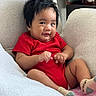 Ethan joined the competition — help win amazing prizes! baby, child, infant, red_onesie, socks, smiling, hair, armchair, fabric, blanket, indoor, person, cute, relaxing, cozy, face, skin, candle, furniture, expression