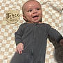 Rian joined the competition — help win amazing prizes! baby, blanket, checkered, child, cute, eyes, floor, hand, happy, head, indoor, infant, lying_down, mouth_open, onesie, person, skin, small, smiling, young