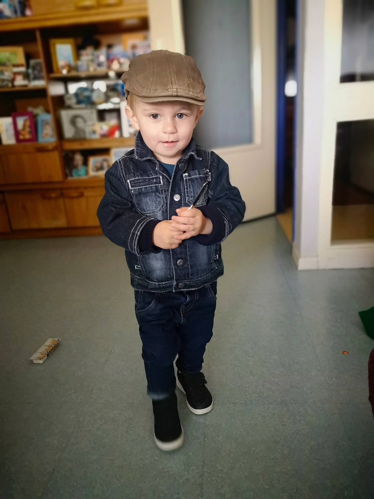 Aaron participe au concours pour gagner de l'argent avec cette photo : baby_toddler_clothing, bookcase, cap, denim, floor, flooring, fun, headwear, jacket, leg, pattern, person, room, shelf, shelving, shoulder, sitting, sleeve, standing, street_fashion