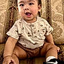 baby, babylaughing, clothing, couch, cushion, face, footwear, furniture, happy, head, homedecor, person, photography, portrait, shoe, shorts, sitting, sleeve, smile, sneaker