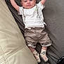arms_up, baby, blanket, child, clothing, couch, cute, face, happy, home, indoor, infant, lying_down, person, relaxed, shorts, smiling, socks, soft_texture, white_shirt