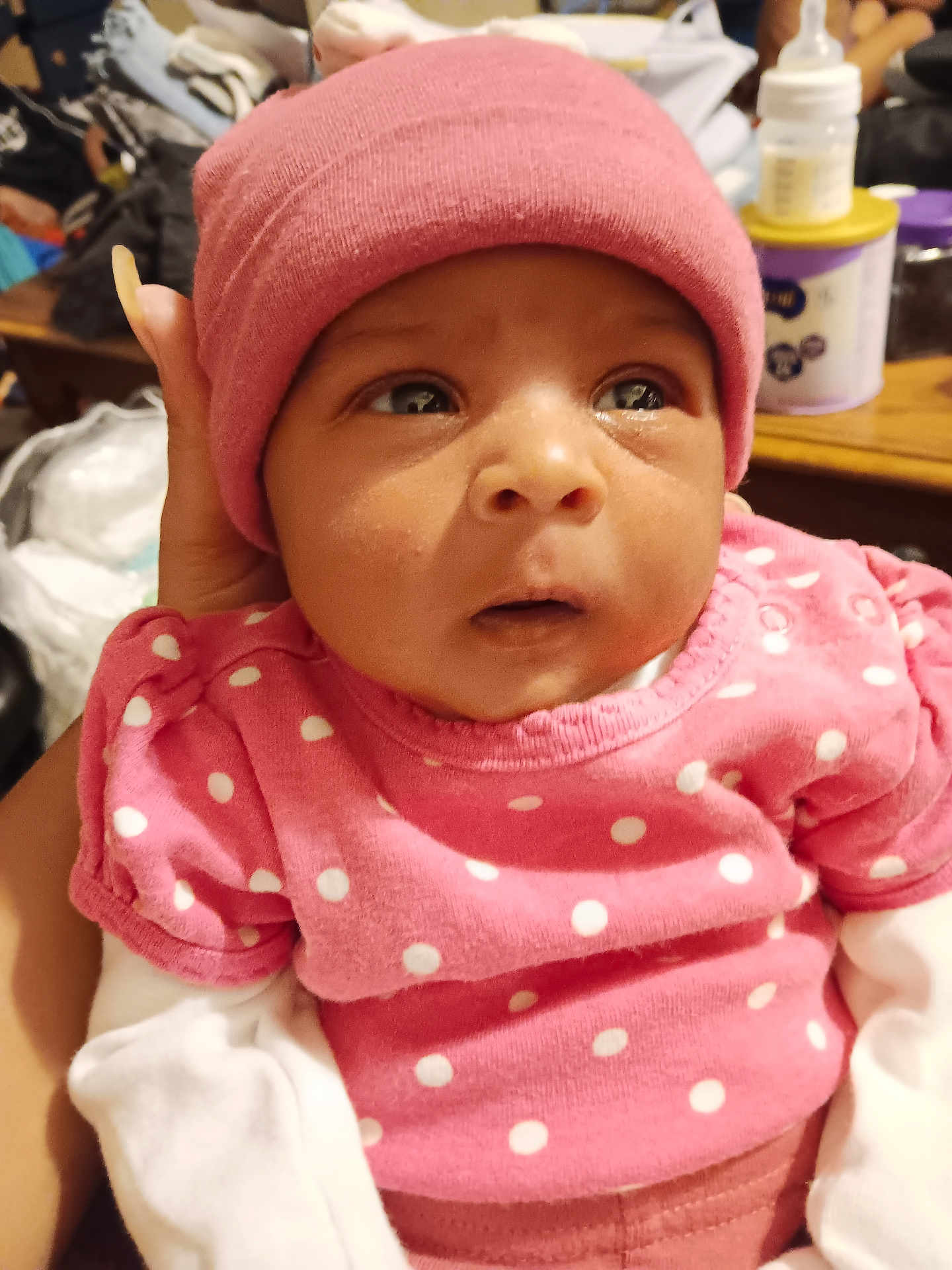 Ra'Taejah is registered to the contest to win money with this photo: baby, infant, pink_hat, pink_clothing, polka_dot, white_sleeves, hand, face, eyes, indoor, person, newborn, portrait, clothing, headwear, expression, supporting_hand, cozy, warm, closeup