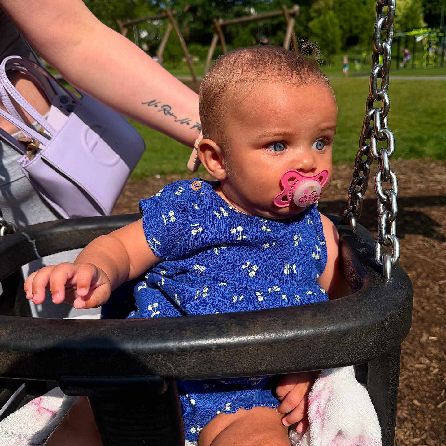 Amalia-Estelle joined the competition — help win amazing prizes! arm, baby, blanket, blue_outfit, chain, child, cute, grass, holding, infant, outdoor, pacifier, park, person, playground, seat, summer, sunlight, swing, tattoo