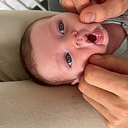 Elio participe au concours pour gagner de l'argent avec cette photo : baby, infant, face, hands, expression, cheeks, blue_eyes, cushion, bottle, blurred_background, close_up, skin, person, indoor, parent, gentle_touch, cute, young_child, human, comfort