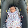 arms, baby, baby_carrier, child, cute, dress, floral, footwear_none, gray, head, infant, legs, outdoor, pavement, peaceful, person, relaxing, skin, sleeping, small