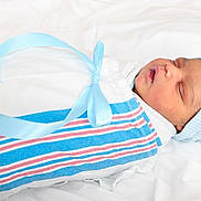 Kaiyzer is registered to the contest to win money with this photo: newborn, baby, sleeping, wrapped, blanket, blue_ribbon, hat, infant, peaceful, soft, white_background, portrait, cute, child, resting, closeup, swaddled, newborn_clothing, baby_boy, indoors