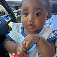 Catherine joined the competition — help win amazing prizes! baby, child, curly_hair, earring, car_interior, steering_wheel, snack, hands, shirt, toddler, seat, window, daylight, face, portrait, cute, expression, sitting, young_child, indoor