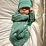 baby, infant, sleeping, onesie, hat, pacifier, bed, pillow, blanket, bedding, indoor, portrait, closed_eyes, hand, footed_pajamas, cozy, newborn, green_outfit, peaceful, cute